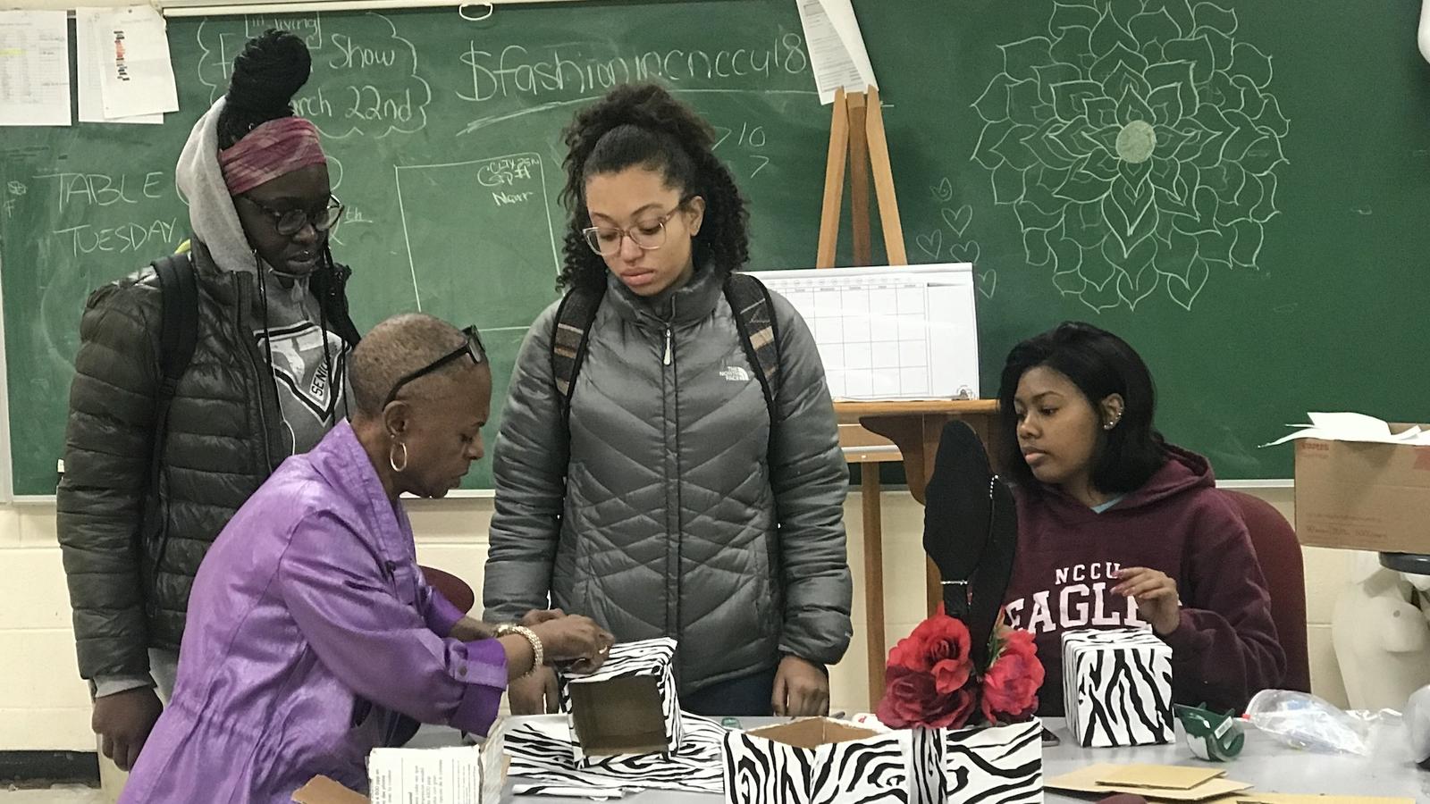 An instructor showing fashion students how to work with fabric