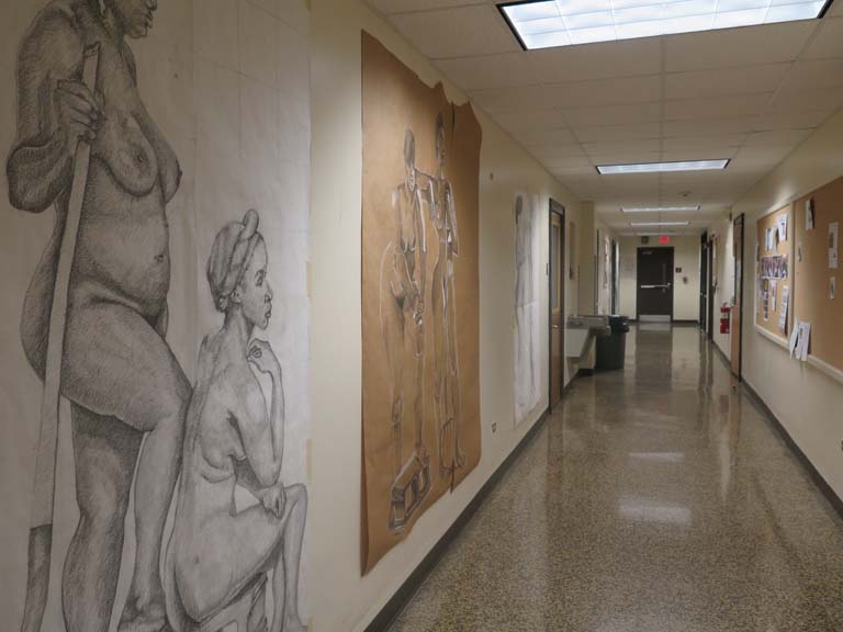 A photo of the Arts building hallway with several art pieces hung on the walls