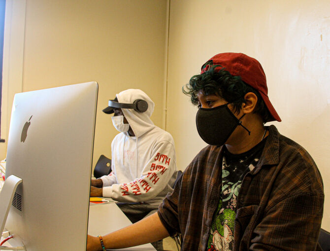 Two students in face masks working at mac computers