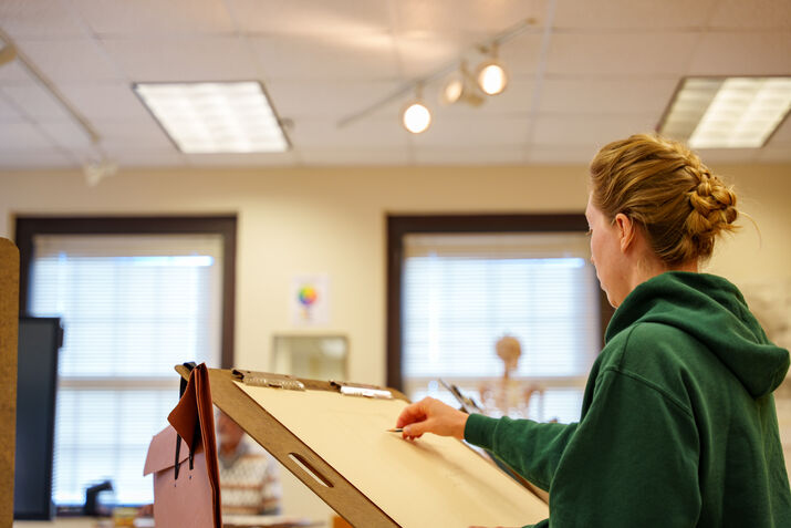 A student drawing on an easel