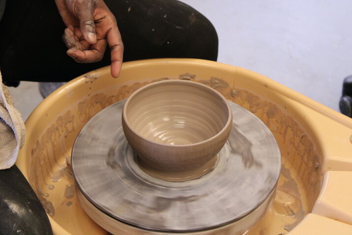 A closeup of a clay bowl in progress on a pottery wheel