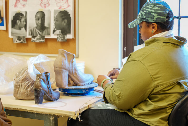 A student crafting a highheel shoe with clay