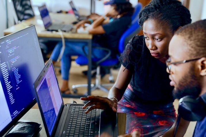 Two students looking at CSS code on a laptop screen