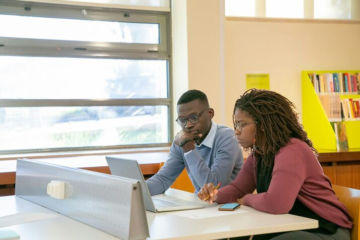 Two people looking intently at a monitor screen