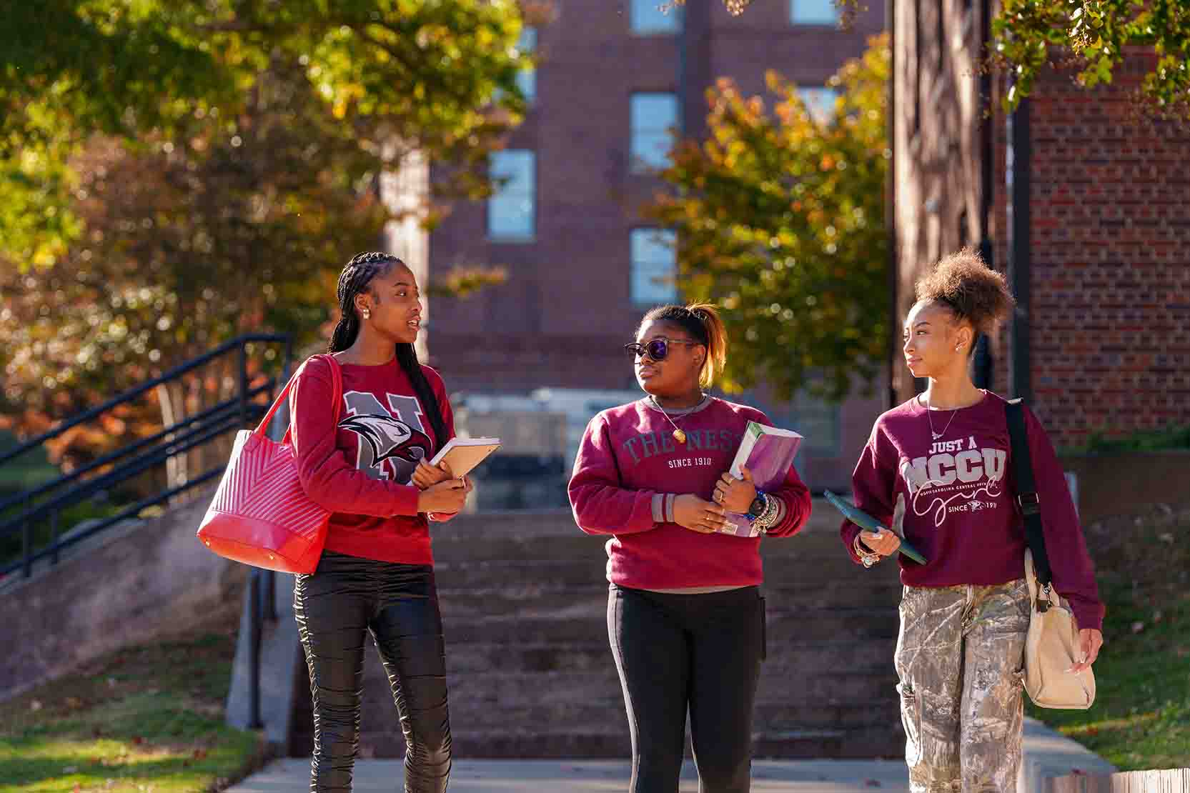 Three students in NCCU attire walking and talking outside