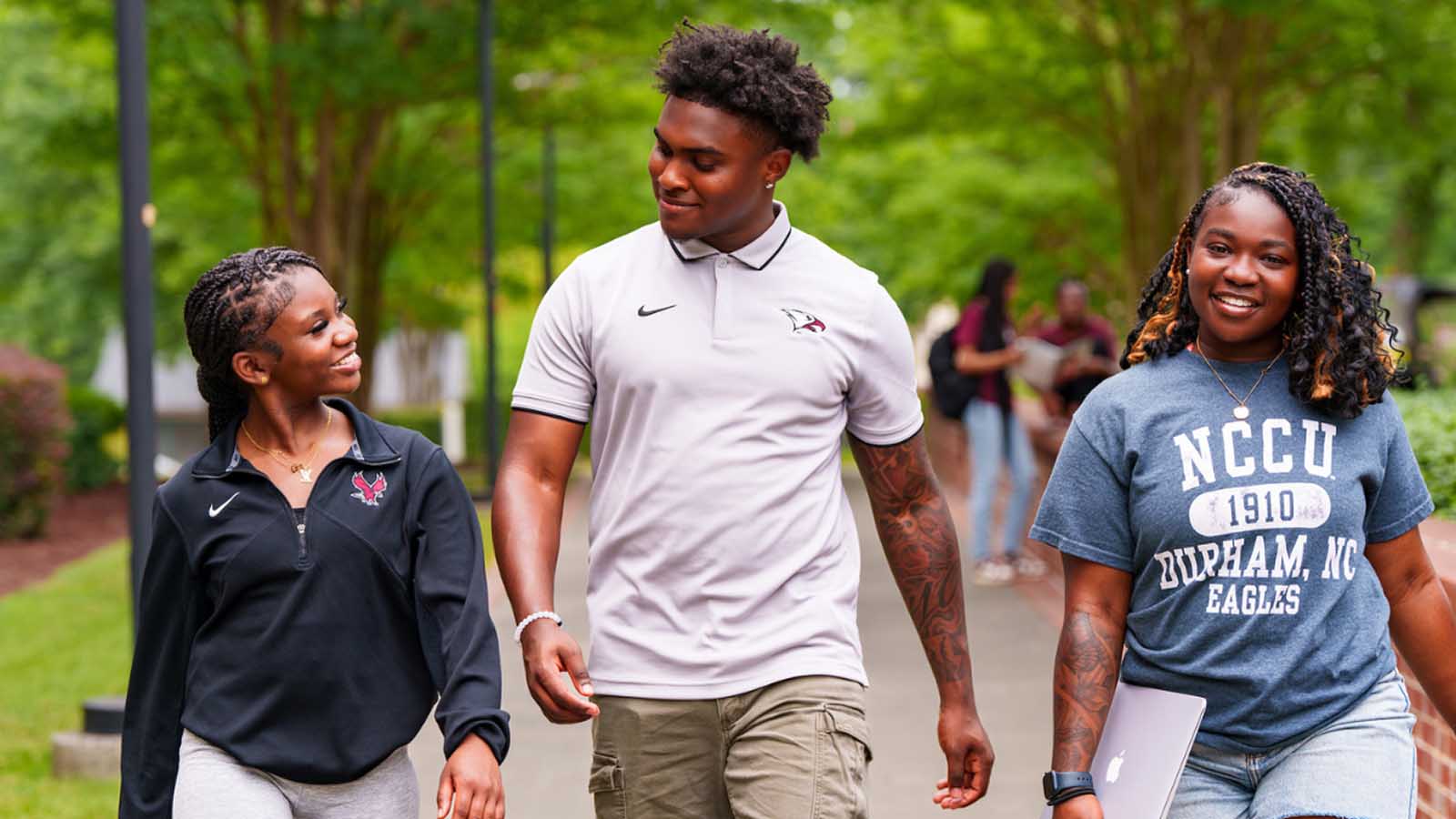 Three NCCU students walking, smiling