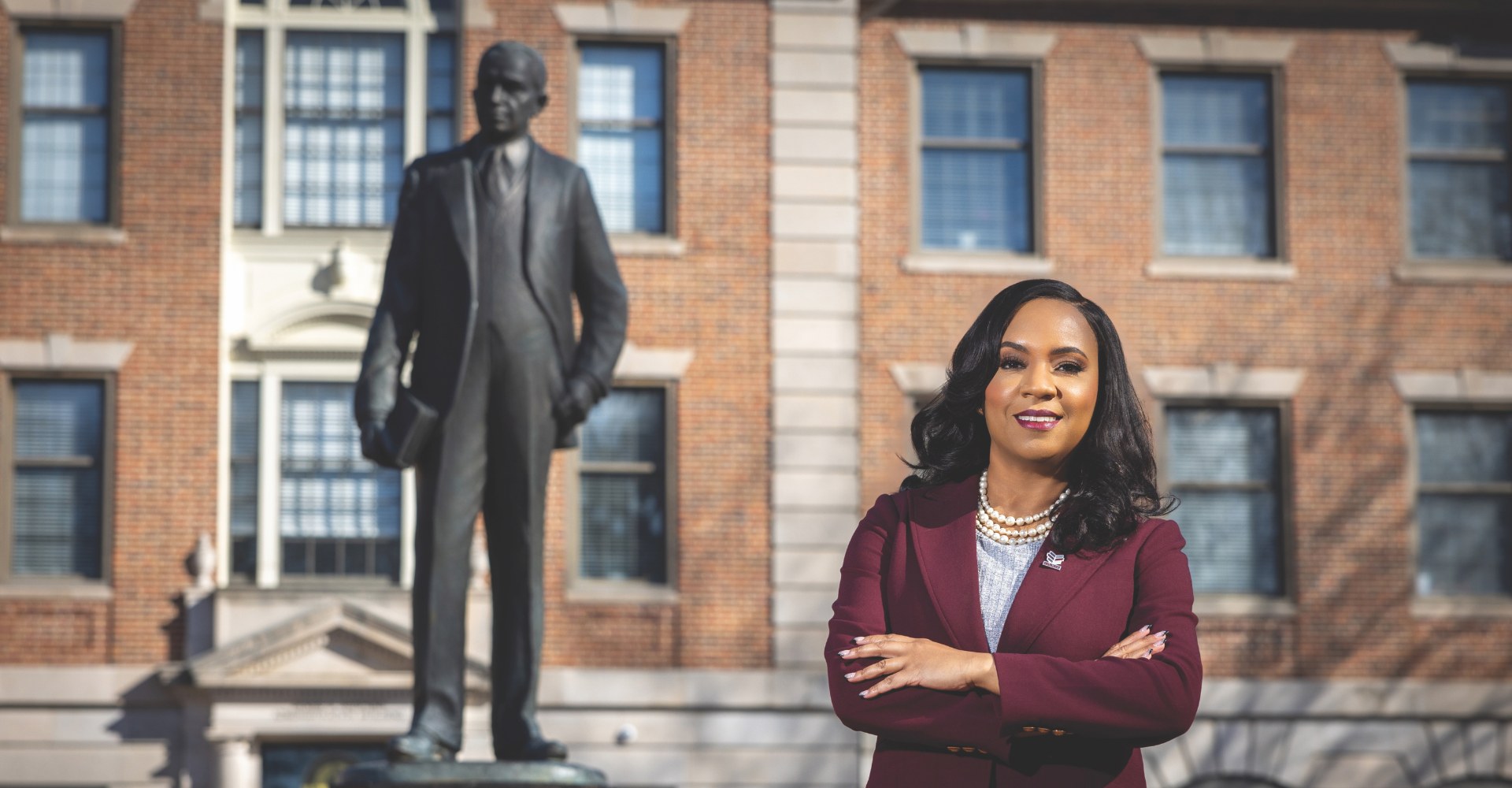 Chancellor Dixon standing beside Dr. Shepard statue outside administration building