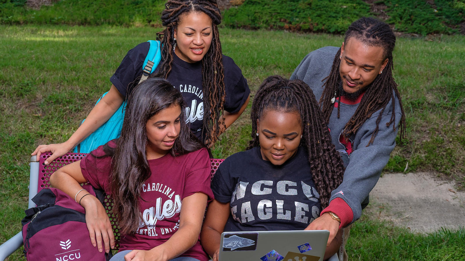 A Group of NCCU students looking at a laptop together while sitting outside