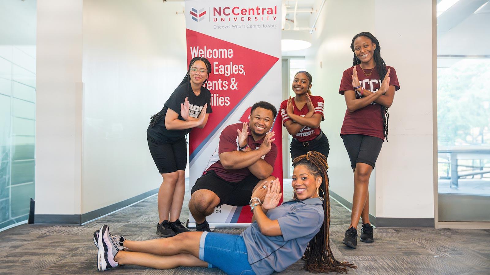 NCCU students and faculty doing the eagle sign in front of a floor banner