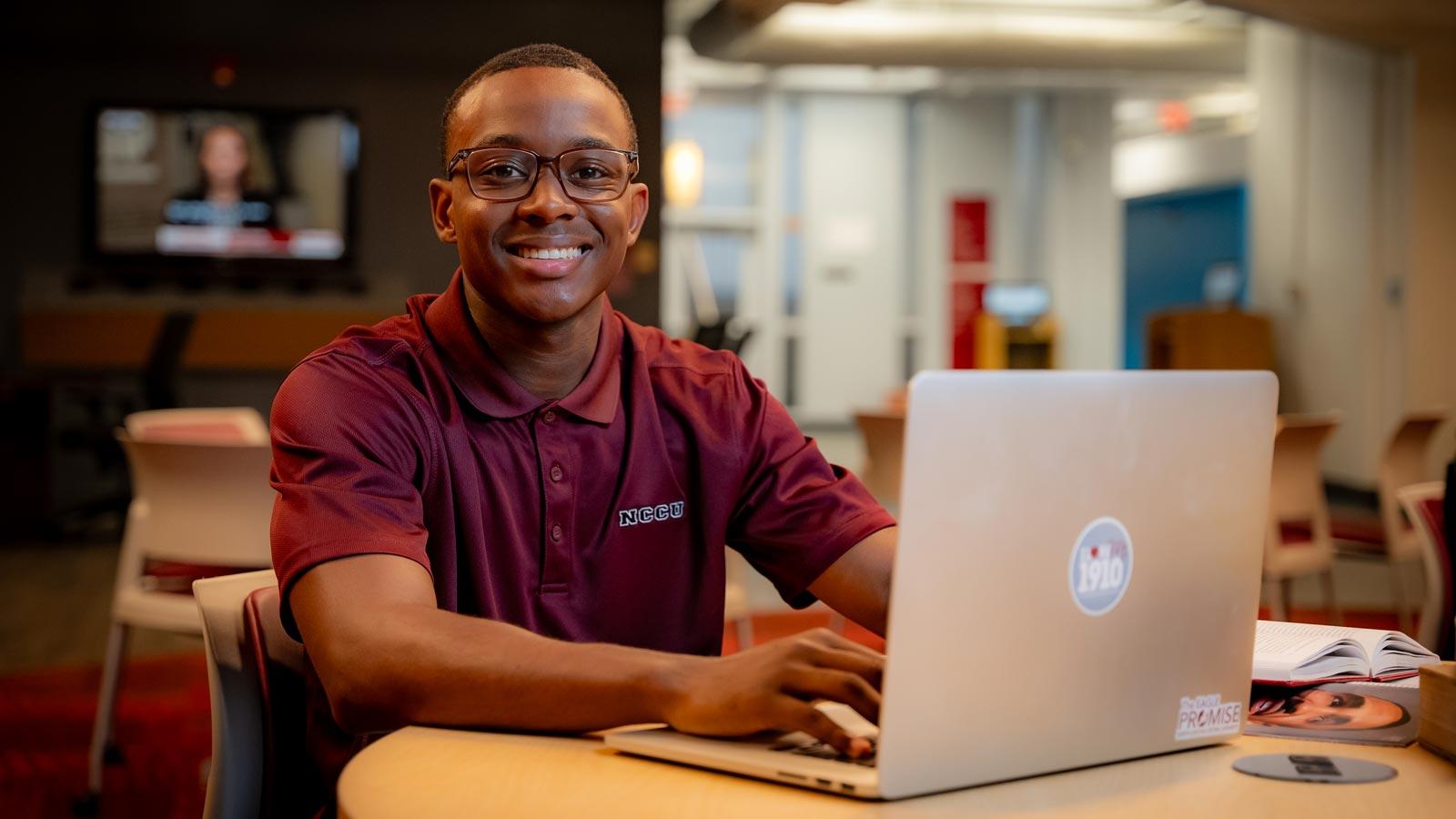 nccu student typing on a laptop, smiling