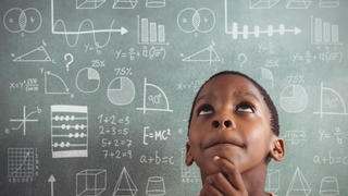 Boy standing in front of a chalkboard with mathematic equations