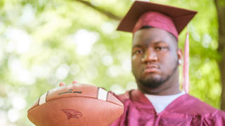 Graduate holding football. 