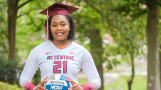 Volleyball player wearing graduation cap while holding volleyball. 