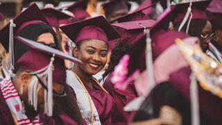 Students seated at the graduation ceremony. One student smiling into the camera