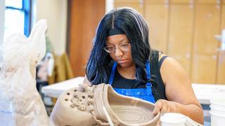 An art student focused on creating a Croc sculpture using clay