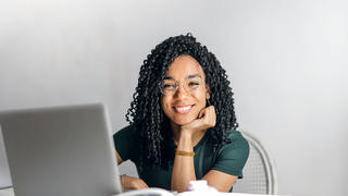 girl working on laptop, smiling at the camera