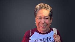 Woman smiling wearing a maroon and white t-shirt.