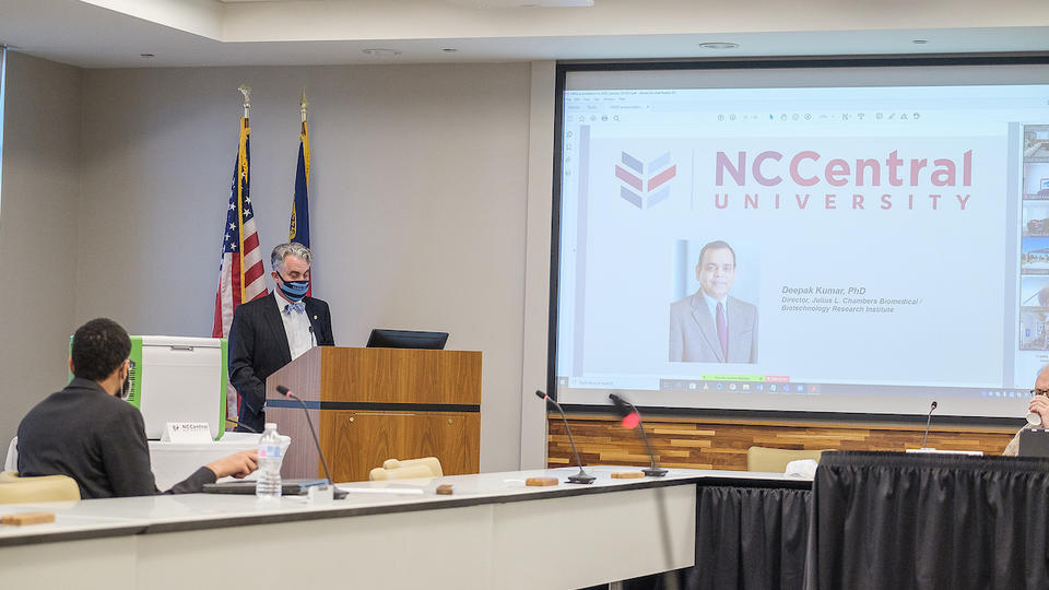 A man in a suit giving a powerpoint presentation