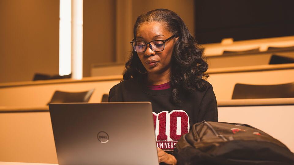 A woman looking at a laptop computer in a lecture hall