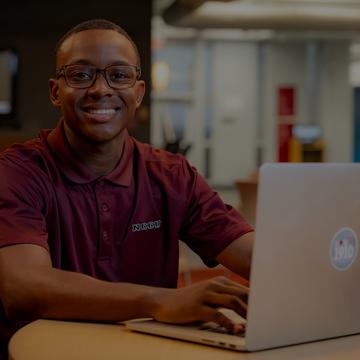 nccu student typing on a laptop, smiling