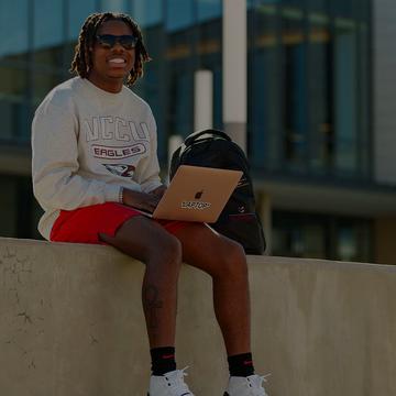 NCCU student sitting down, using laptop, smiling